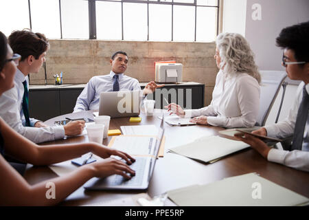 Male manager brainstorming with team in meeting room Stock Photo