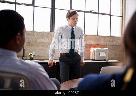 Young male manager stands listening at a meeting, close up Stock Photo