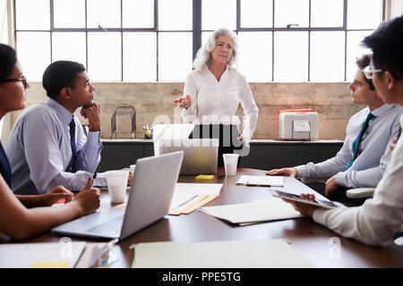 Female boss stands addressing team at informal work meeting Stock Photo ...