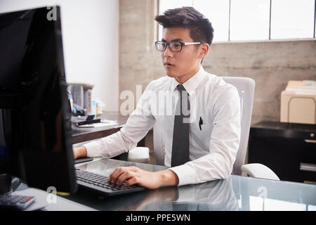Young Asian businessman using a computer at an office desk Stock Photo