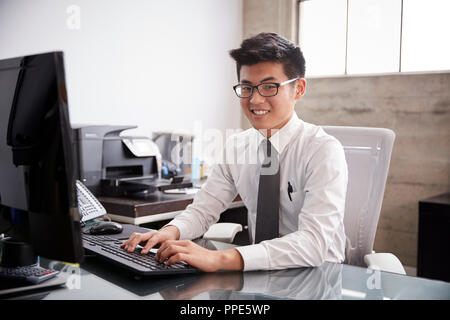 Young Asian businessman using a computer,  smiling to camera Stock Photo