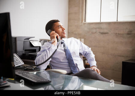 Mixed race businessman at an office desk using the phone Stock Photo