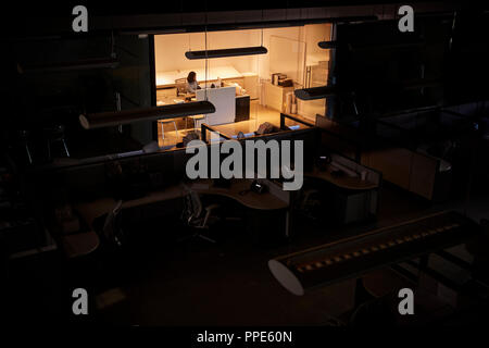 Office worker working late in an otherwise dark office Stock Photo
