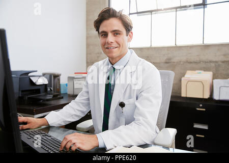 Young white male doctor using computer smiling to camera Stock Photo