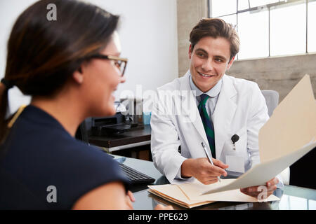White male doctor showing file to female patient in office Stock Photo
