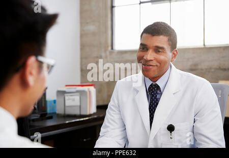Smiling mixed race male doctor in consultation with patient Stock Photo