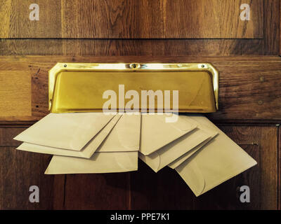Mails in the letter slot of a wooden door. Stock Photo
