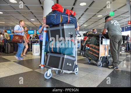 Travelers stand in line during the holiday season in front of a check-in counter at the Munich Airport. Stock Photo