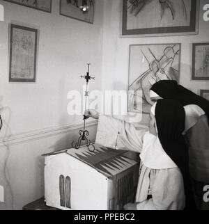 1950, two catholic nuns in a room with sketches on the walls and with a model of the Chapelle du Rosaire de Vence (Rosary Chapel).  The building of the chapel on the French Riviera was a project conceived and decorated by the artist Henri Matisse towards the end of his life and which was considered by the painter himself as his final masterpiece. Stock Photo