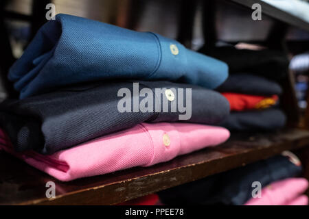shirts of different colors folded and exposed in fashion store Stock Photo