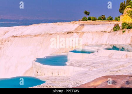 The enchanting pools of Pamukkale in Turkey. Pamukkale contains hot springs and travertines, terraces of carbonate minerals left by the flowing water. Stock Photo