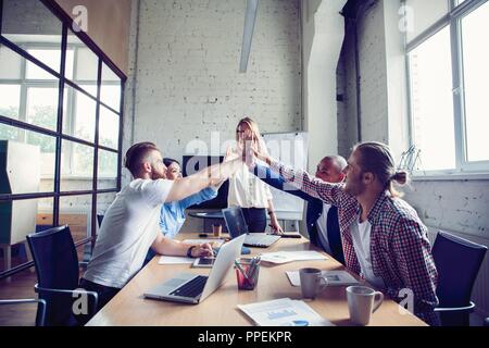 Happy successful multiracial business team giving a high fives gesture as they laugh and cheer their success. Stock Photo