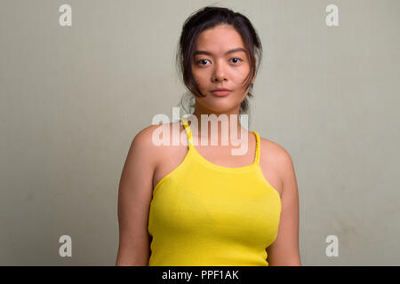 Young beautiful Asian woman wearing yellow sleeveless top Stock Photo