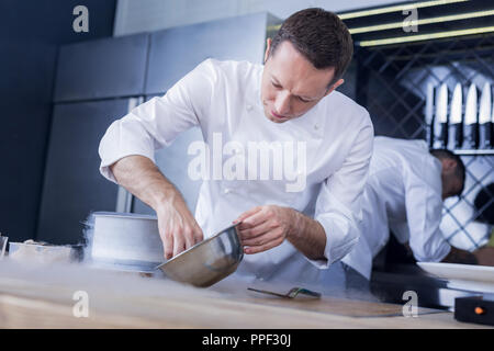 Concentrated pleasant cook doing his work perfectly Stock Photo