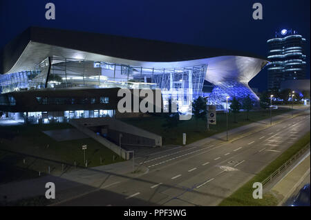 The illuminated BMW Welt in Munich at night. Right the company's headquarters in the so-called Four Cylinder. Stock Photo