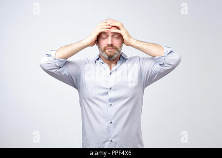 Studio portrait of upset worried sad, depressed, tired man with a headache and very stressed face Stock Photo