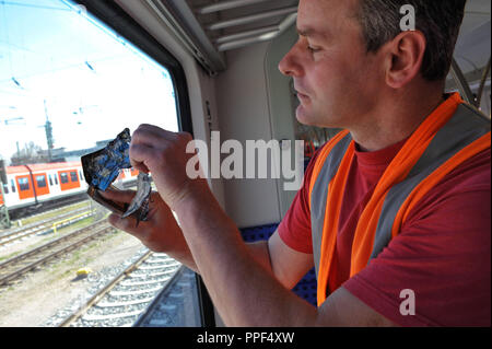 The cleaning personnel of Deutsche Bahn doing the daily cleaning of S-Bahn trains. The picture shows the removal of a sticker from a window. Stock Photo