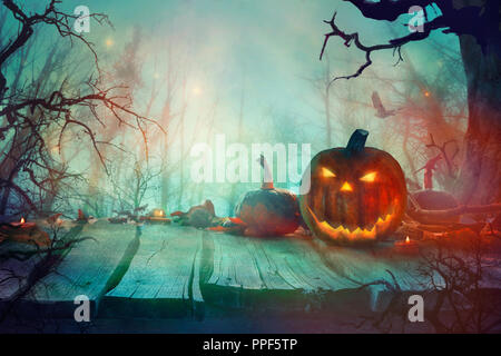 Halloween with Pumpkins and Dark Forest. Scary Jack O' Lantern Halloween Design on Table Stock Photo