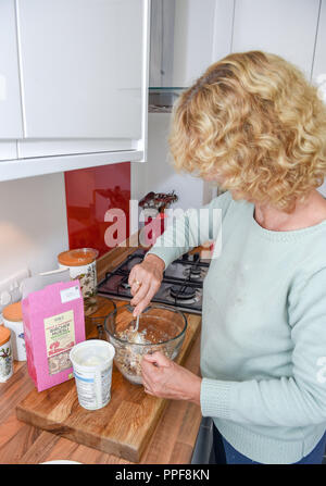 Mature woman making healthy breakfast of Bircher muesli with  yoghurt Stock Photo