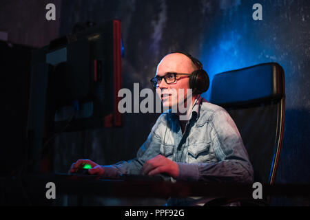 young male video game addict in the hood playing shooters in the night Stock Photo