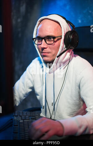 technology, gaming, entertainment, let's play and people concept - happy young man in eyeglasses with headset playing and winning computer game at home and streaming playthrough or walkthrough video Stock Photo