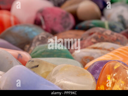 Polished colorful semi-precious gemstones background. Macro shot of tumbled precious stones. Beautiful rounded natural stones background image. Stock Photo