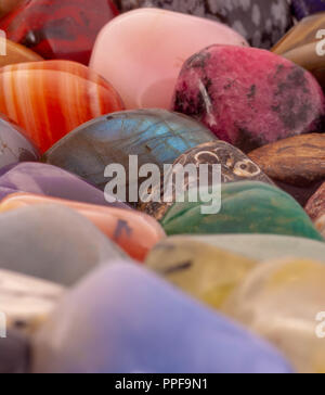Polished colorful semi-precious stones background. Macro shot of tumbled precious healing stones. Beautiful rounded natural stones background image. Stock Photo