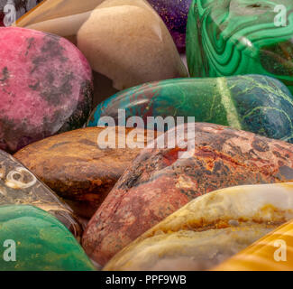 Tumbled gemstones background. Macro shot of polished precious stones. Beautiful natural stones background image. Rhodonite, malachite, jasper and more Stock Photo