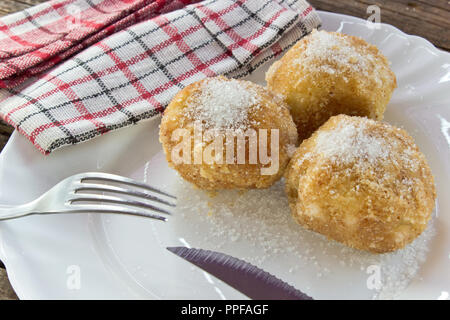 Plum dumplings on plate with fork on wooden table Stock Photo