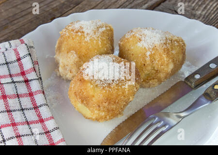 Plum dumplings on plate with fork on wooden table Stock Photo
