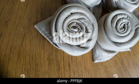 Four golden napkin origami roses over a wooden background ready for events, parties, celebrations and holidays table decorations Stock Photo