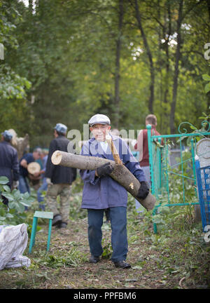 Tatarstan, Russia - 25 august 2018 - an old man carrying a huge stick from sawn tree in a forest Stock Photo