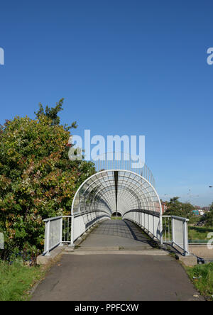 Enclosed pedestrian footbridge with steel safety cage, over m60 motorway at junction 17, whitefield interchange in greater manchester uk Stock Photo