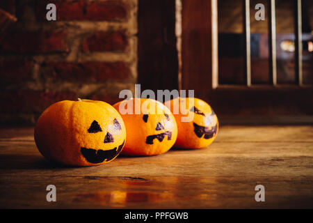 Three Oranges with Halloween Head Pumpkins haunted spooky face painted on the floor.  Decoration for Halloween festival. Stock Photo