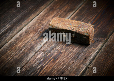 Head of an old rusty hammer without haft lying on old wooden board Stock Photo