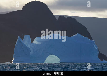 Iceberg in front of a mountain silhouette at Niaqornat, Umanak Fjord, Greenland Stock Photo
