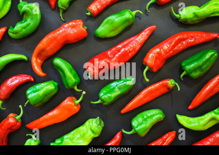 Red and green peppers shapes pattern on a dark background. Vegetables and food abstract background. Top view. Organic food and shapes. Stock Photo
