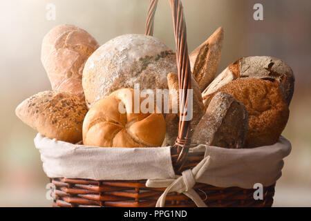 Assortment of breads over a wicker basket in a rustic kitchen. Horizontal composition. Front view Stock Photo