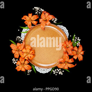 Beautiful orange lilies flowers and empty clay plate, isolated on a black background Stock Photo