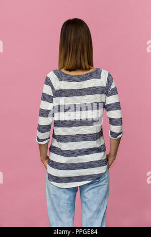 Young woman with brown hair back portrait. Rear view against pink background Stock Photo