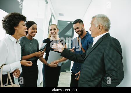 business people standing together in office having casual discussion. Corporate professional having informal meeting in office corridor. Stock Photo