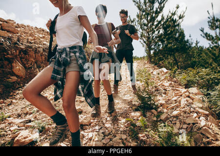 Explorer friends walking down a rocky path in a forest. Group of friends on a vacation exploring the country side. Stock Photo