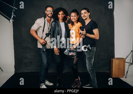 Photographer with his crew and model standing in a photo studio. Studio shot of cameraman with a female model and assistants. Stock Photo