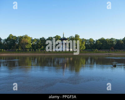 Thames river and Battersea Park in London, England. Beautiful green trees against blue sky. The Peace Pagoda is seen in the park. Stock Photo