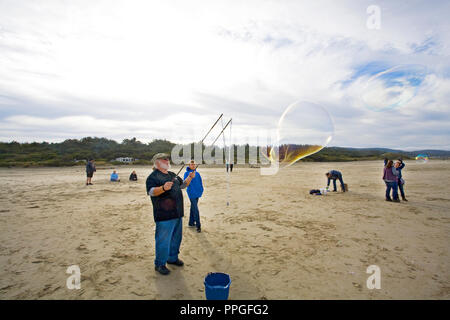 A man using a bubble wand to creat huge soap bubbles at a bubble blowing festival near yachats, Oregon Stock Photo