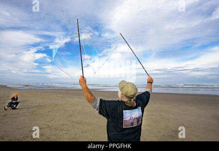 People on an Oregon beach near yachats, blowing bubbles using a bubble wand. Stock Photo
