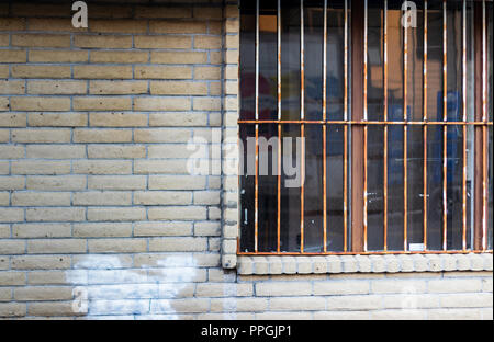 Old abandoned building window with rusty bars and deteriorated brick wall Stock Photo