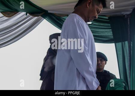 Lhokseumawe, Aceh, Indonesia. 25th Sep, 2018. A man seen in pain while being whipped in public for gambling which is considered to violate the Islamic Sharia law.Although considered to violate the International Convention against Cruel, Inhuman or Torture and Cruelty. Aceh, one of the provinces in Indonesia that insists on carrying out whipping as a province of Islamic Sharia law. Credit: Maskur Has/SOPA Images/ZUMA Wire/Alamy Live News Stock Photo
