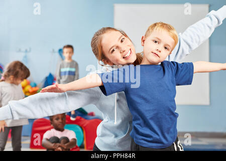 Boy doing stretching exercise together with wife as a teacher or sports teacher Stock Photo