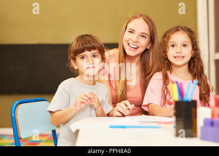 Young woman as a teacher or childminder together with two girls in kindergarten Stock Photo